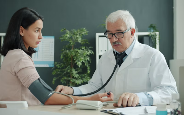 Male doctor in a white coat writing notes at a desk with medication bottles